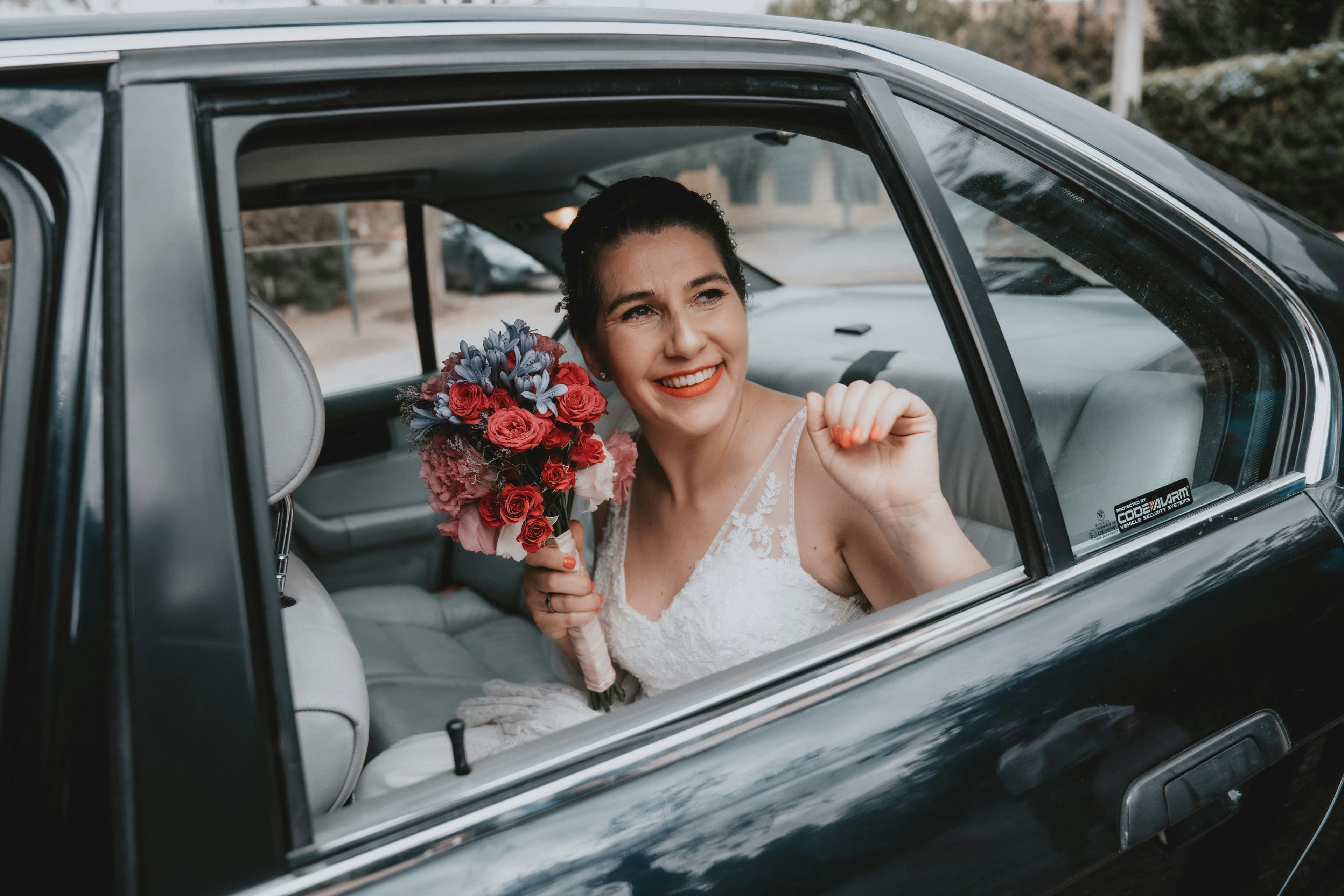 Bride sitting in car holding flowers