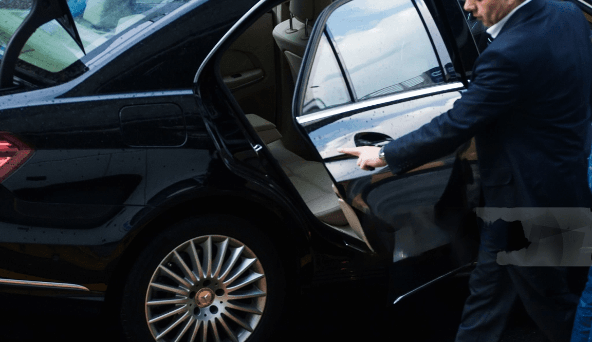 Man in suit opening the door to a luxury vehicle